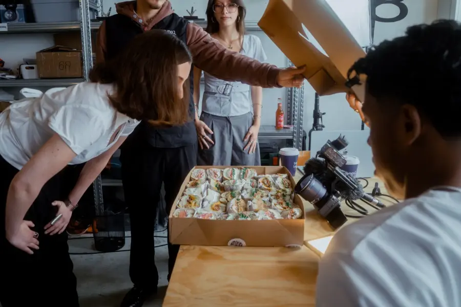 team packing a catering box of bagels behind the scenes