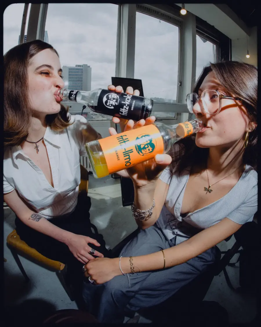 two friends drinking fritz kola with their bagels