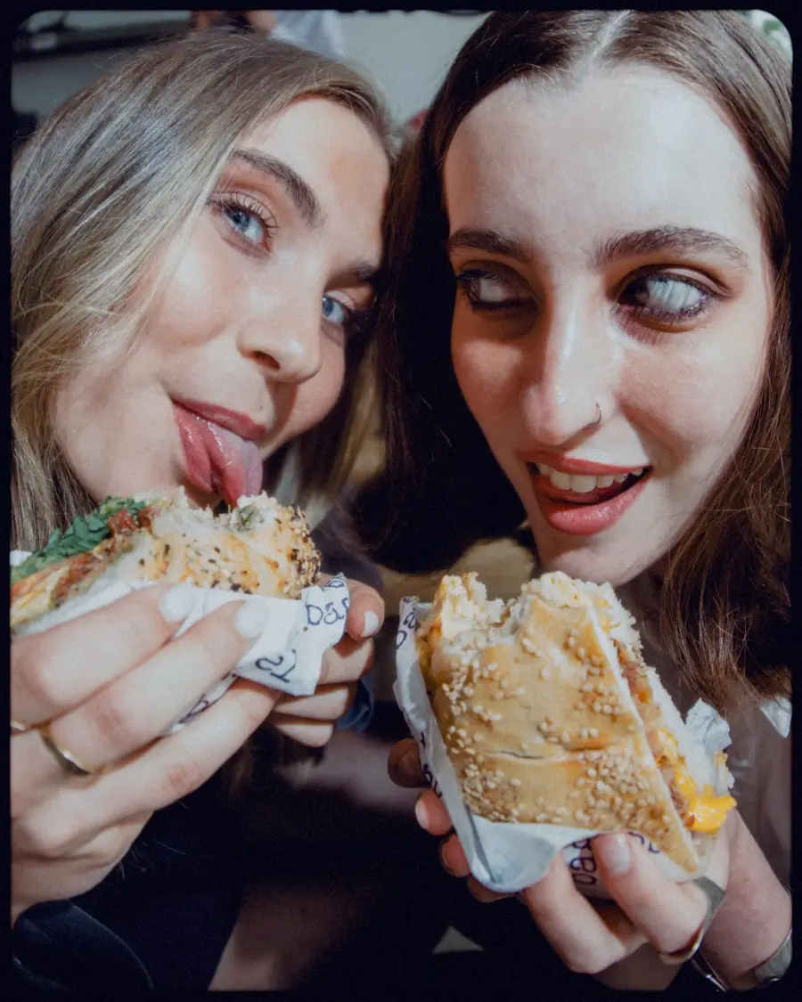 friends biting into fresh sesame bagels
